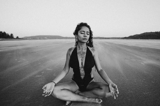 Build a foundation with meditation - A women meditating on a dirt road black and white - Cadence Haven Blog
